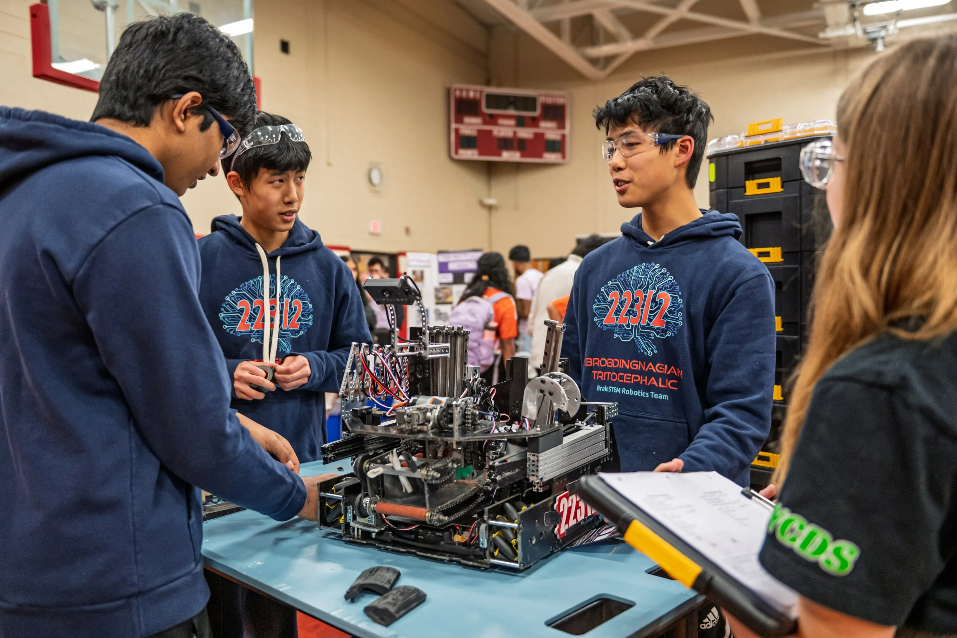 Members of FIRST Tech Challenge team 22312 in BrainSTEM hoodies standing around their robot on a pit table at the Pennsylvania state championship, talking with a judge holding a clipboard.